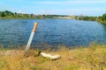 Against the background of the pond and factory pipes stuck in the ground, next to a gas mask