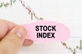 Against the background of the quote chart, a man holds a sign with the inscription - stock index