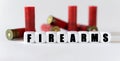 Against the background of rifle cartridges, there are white cubes with text FIREARMS
