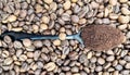 Against the background of roasted aromatic coffee beans lies a metal spoon filled with ground coffee. A drink made from Royalty Free Stock Photo