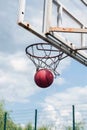 Against the background of the sky, a basketball hoop with a ball in the net Royalty Free Stock Photo