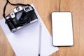 Against the background of the desk- vintage photo camera, digital tablet with a white mock up screen, a blank white sheet for Royalty Free Stock Photo