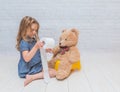 Against the background of a white brick wall, the girl sits on a Royalty Free Stock Photo