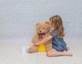 Against the background of a white brick wall, the girl sits on a Royalty Free Stock Photo