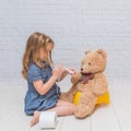 Against the background of a white brick wall, the girl sits on a Royalty Free Stock Photo