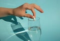 Against a blue background, a hand drops a dissolving fizzy aspirin tablet into a glass of water Royalty Free Stock Photo