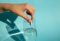 Against a blue background, a hand drops a dissolving fizzy aspirin tablet into a glass of water Royalty Free Stock Photo