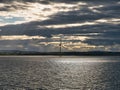 Against dark clouds and bright sunshine a single wind turbine is silhouetted off the coast of Aberdeen in Scotland, UK Royalty Free Stock Photo
