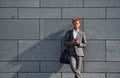 Against grey wall. Young businessman in grey formal wear is outdoors in the city Royalty Free Stock Photo