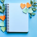 Against a light blue background, a blank notepad is paired with a collection of colorful notes shaped like hearts Royalty Free Stock Photo