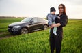 Against he modern car. Mother with her little baby son is outdoors on the agricultural field Royalty Free Stock Photo