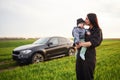 Against he modern car. Mother with her little baby son is outdoors on the agricultural field Royalty Free Stock Photo