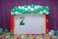 Colorful baby carpet. White and green balloons. Pink curtain.Two inscriptions with green artificial flowers. 2 Age decor