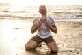 Age is just a number! In healthy body - healthy mind. Handsome fit muscular senior posing in the ocean at sunset time