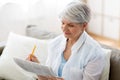 Senior woman marking newspaper ad at home