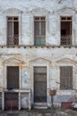 Aged abandoned vintage grunge house facade with broken door and windows and weathered shutters