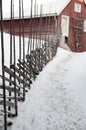 Aged agricultural red traditional barn on idyllic rural farmland, ranch road with snow and rustic old wooden fence Royalty Free Stock Photo