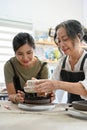 Aged asian woman and young asian woman making a ceramic cup together