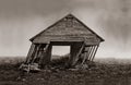 An aged barn leans and nears collapse in this vintage sepia photograph