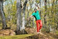 An aged bearded man in orange pants walks on a slack stretched between trees in an autumn forest. The concept of balance Royalty Free Stock Photo