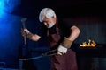 Aged blacksmith hitting steel with hammer at forge