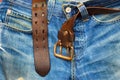 Aged blue jeans with unfastened old leather belt Royalty Free Stock Photo