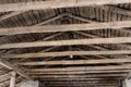 Aged brown wooden timber beam on roof ceiling inside old farm or ranch building interior. Rural gabled roof old