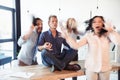 Aged businessman sitting on table and meditating in lotus position while colleagues running around Royalty Free Stock Photo