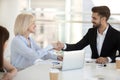 Aged businesswoman shaking hands with client sitting together in boardroom Royalty Free Stock Photo