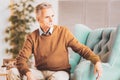 Aged concerned man sitting in light modern living room