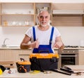 Aged contractor repairman working in the kitchen