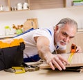 Aged contractor repairman working in the kitchen