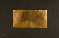 Aged copper plate on black cloth, old worn metal background. Royalty Free Stock Photo