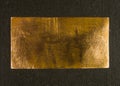 Aged copper plate on black cloth, old worn metal background. Royalty Free Stock Photo