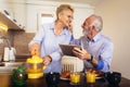 Senior couple busy look at digital tablet while having delicious breakfast at home kitchen Royalty Free Stock Photo