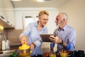 Couple busy look at digital tablet while having delicious breakfast at home kitchen Royalty Free Stock Photo