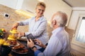 Senior couple busy look at digital tablet while having delicious breakfast at home kitchen Royalty Free Stock Photo