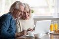 Senior couple using laptop while having breakfast at home Royalty Free Stock Photo