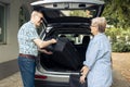 Aged couple putting bags in vehicle trunk Royalty Free Stock Photo