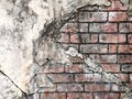 An aged, cracked and chipped stucco wall with an area of exposed brown brick. Brick wall background texture.