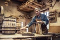 An aged craftsman builds wooden barrels in his vintage workshop