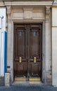 Aged dark wood double door entrance of old building in Paris France. Antique wooden door panels with golden metal handles. Royalty Free Stock Photo