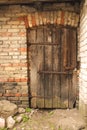 Aged dark wooden door in weathered dirty wall Royalty Free Stock Photo