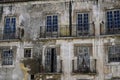 Aged and deteriorated building featuring multiple windows and doors in a state of disrepair