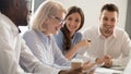 Aged female boss positive staff working together sitting at boardroom Royalty Free Stock Photo