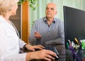 Aged female doctor talking with mature male patient Royalty Free Stock Photo