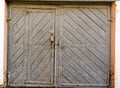 The aged gates of old garage. Gray color and little door.