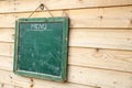 Aged green menu blackboard hanging on wooden wall Royalty Free Stock Photo