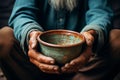 Aged hands clutch empty bowl, selective focus conveying the harshness of poverty Royalty Free Stock Photo