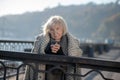 Aged homeless woman with coat on shoulders holding cup of tea Royalty Free Stock Photo